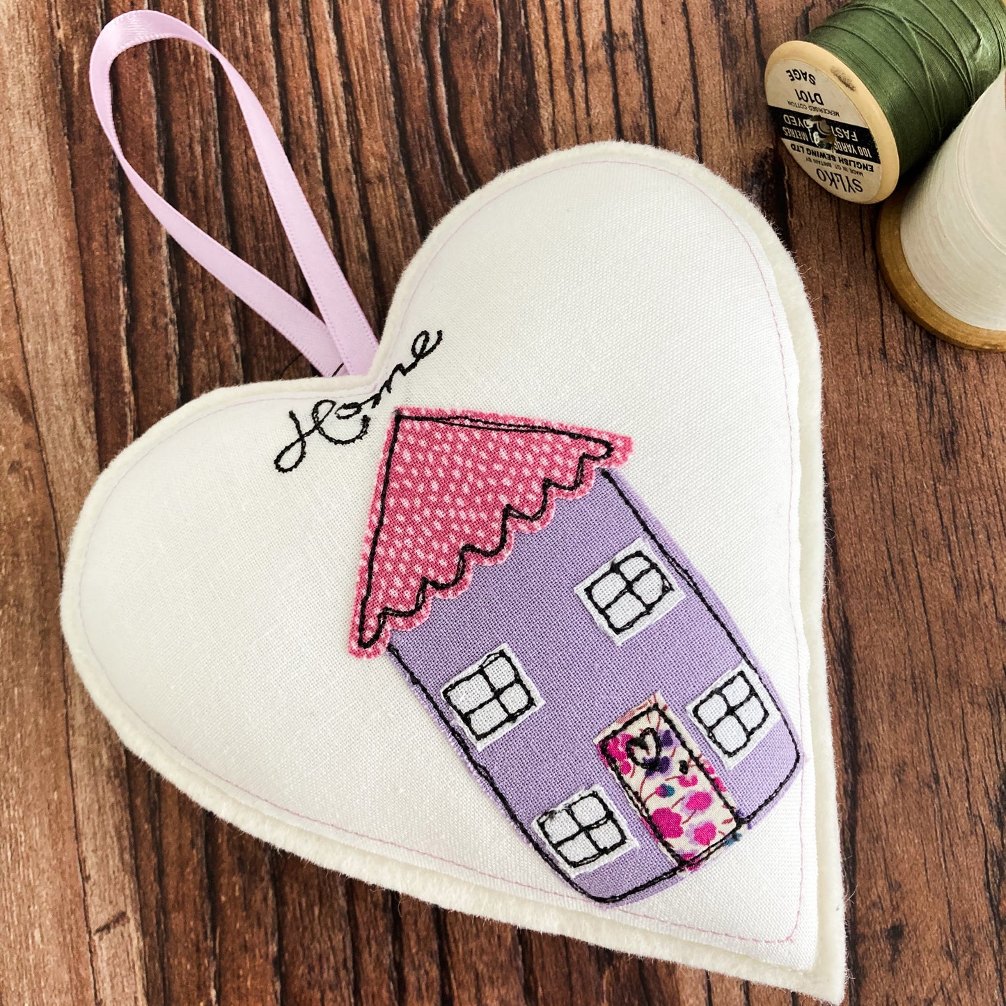 Applique lilac house with the word Home all stitched onto white cotton and a white woollen felt heart with lilac ribbon