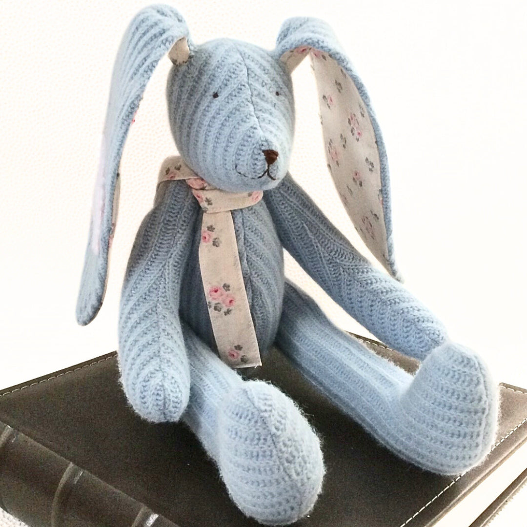 Blue Keepsake Bunny with scarf sat on a book