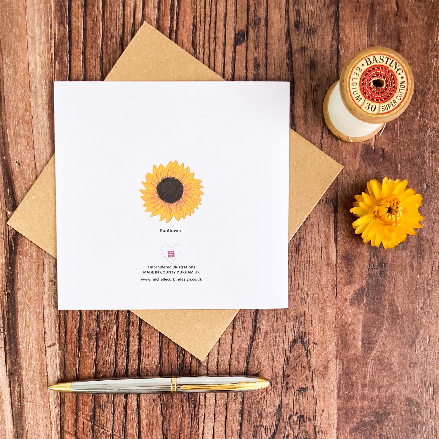 Reverse of Sunflower card, with a small sunflower, words, plus one brown envelope, a pen, basting thread and a dried flower